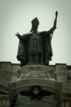 Statue of individual, staff in hand and both arms open